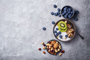 Wall Mural - Bowl of healthy breakfast with granola, yogurt, fresh fruits, berries and nuts