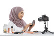© Odua Images - excited hijab woman blogger holding powder for makeup and making videos to review cosmetic products to share on website or social media
