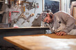 © astrosystem - Male carpenter working on old wood in a retro vintage workshop.