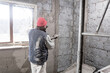 © astrosystem - Real construction worker working on a wall inside the new house.