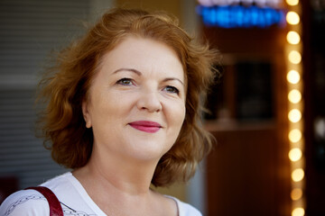 Wall Mural - Beautiful mature lady with red hair walks outside.