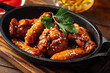Cast iron plate of fried chicken wings in teriyaki sauce