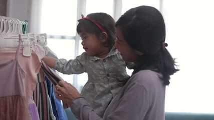 Wall Mural - beautiful asian mother taking her daughter to buy clothes in the shopping mall