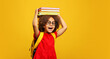 © ShunTerra - funny smiling Black child school girl with glasses hold books on her head