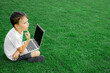 © vovan - child sits on the grass and studies with a laptop online, enjoying nature