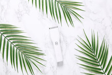 Hair Clipper On A Marble Background With Palm Leaves.