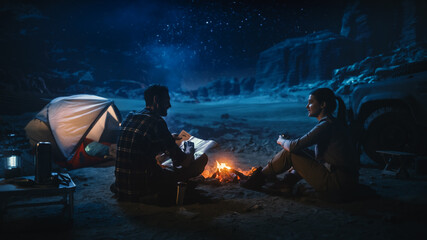 Wall Mural - Happy Couple Camping in the Canyon Wilderness at Night Together, Sitting by Campfire, Plan Hiking Journey with a Map. Two Traveling Hikers Talk, Milky Way Star Watching. Vacation Trip in Wilderness