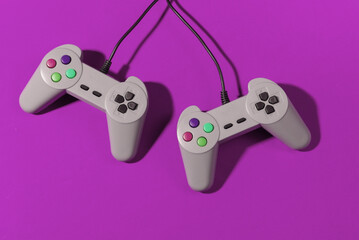 Wall Mural - Retro gamepads on pink background with shadow. Retro gaming. Top view