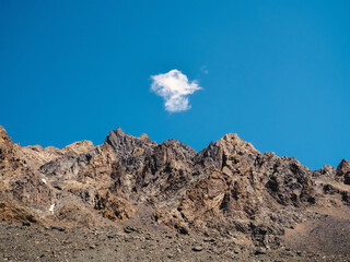 Small white cloud over a rocky mountain range. Mountain natural minimalistic background.