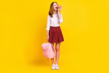 Wall Mural - Full body photo of nice little girl eat apple wear shirt skirt bag sneakers isolated on yellow background