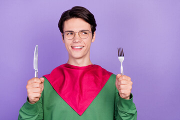 Sticker - Photo of young handsome guy happy positive smile lick teeth hungry food cutlery isolated over violet color background