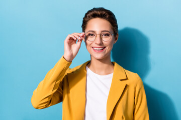 Poster - Photo of young attractive woman happy positive smile hand touch eyeglasses isolated over blue color background