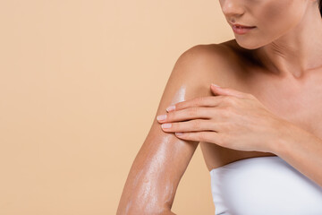 cropped view of young woman applying sunblock isolated on beige