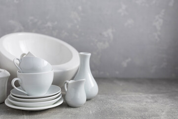 Poster - Empty crockery set or ceramic dishes. White kitchen dishware and tableware on table near grey wall