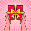Hands holding red gift box or present with a bow and ribbons. Pop art vector comic illustration. Top view.
