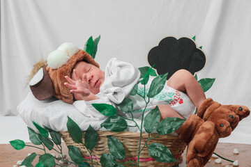  Beautiful newborn baby (4 days old), with hat and puppy shoes, dreaming, in bamboo fiber basket and surrounded by green leaves, Healthy medical concept
