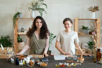 Poster - Two young females standing by table while one of them cutting hard soap mass