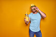 © zamuruev - Creative male in sunglasses and summer clothes, stylish hat standing relaxed and drinking from creative cocktail bottle