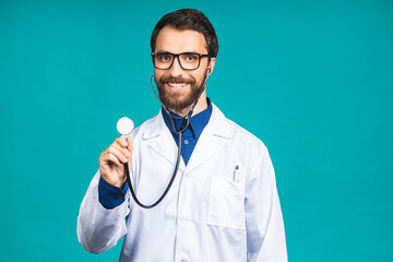 Wall Mural - Portrait of young bearded doctor man with stethoscope over neck in medical coat standing against isolated blue background.