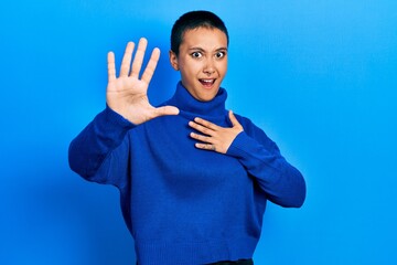 Poster - Beautiful hispanic woman with short hair wearing turtleneck sweater afraid and terrified with fear expression stop gesture with hands, shouting in shock. panic concept.