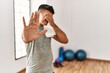 Young hispanic man wearing sportswear and towel at the gym covering eyes with hands and doing stop gesture with sad and fear expression. embarrassed and negative concept.