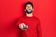 © Krakenimages.com - Young arab man with beard holding television remote control angry and mad screaming frustrated and furious, shouting with anger looking up.