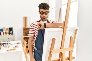 Sticker - Arab young man at art studio looking at the watch time worried, afraid of getting late