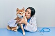 © Krakenimages.com - Veterinarian woman wearing uniform at the clinic, hugging dog with love