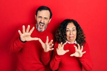 Poster - Middle age couple of hispanic woman and man hugging and standing together afraid and terrified with fear expression stop gesture with hands, shouting in shock. panic concept.