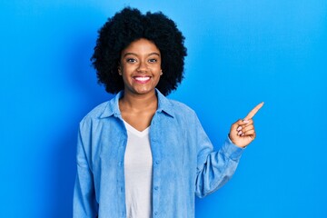 Young african american woman wearing casual clothes with a big smile on face, pointing with hand finger to the side looking at the camera.