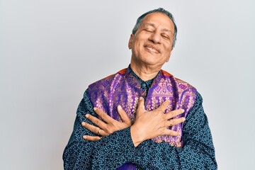 Poster - Middle age indian man wearing traditional indian clothes smiling with hands on chest, eyes closed with grateful gesture on face. health concept.