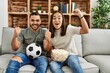© Krakenimages.com - Young latin couple watching soccer match eating porpcorn at home.