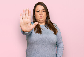 Beautiful brunette plus size woman wearing casual clothes doing stop sing with palm of the hand. warning expression with negative and serious gesture on the face.