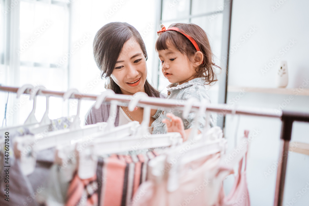 beautiful asian mother taking her daughter to buy clothes - obrazy, fototapety, plakaty 