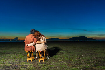 Canvas Print - couple in love sitting and hugging at the grass filed at night