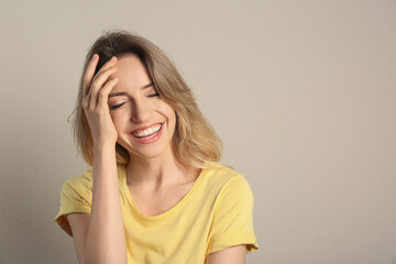 Wall Mural - Portrait of happy young woman with beautiful blonde hair and charming smile on beige background. Space for text