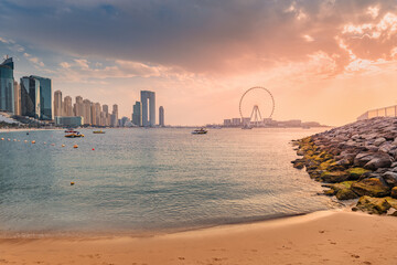 A delightful and colorful sunset over Blue waters Island with the famous Dubai Eye Ferris wheel. Panoramic view of the city in UAE