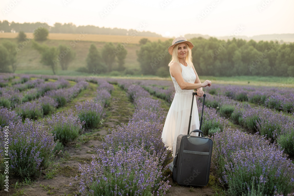 woman with luggage in lavender field - obrazy, fototapety, plakaty 