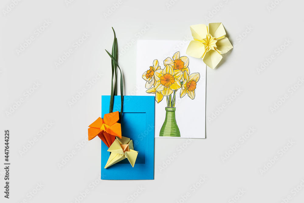 Origami narcissus flowers and greeting card on white background