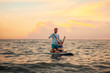 © _KUBE_ - Instructor and pre-school girl to surfing on a sup board. Sea and the sunset in the background. Summer vacations