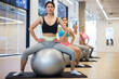 © JackF - Portrait of focused young adult woman practicing pilates with big exercise ball at group workout