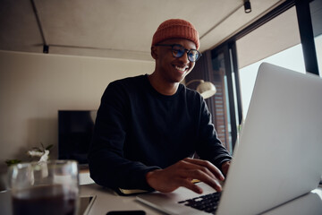 African American male working from home and typing on his laptop. African American male using electronics to work from home. High quality photo