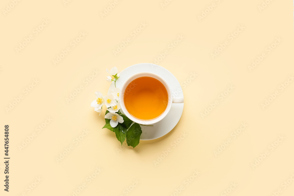 Cup of jasmine tea and flowers on color background