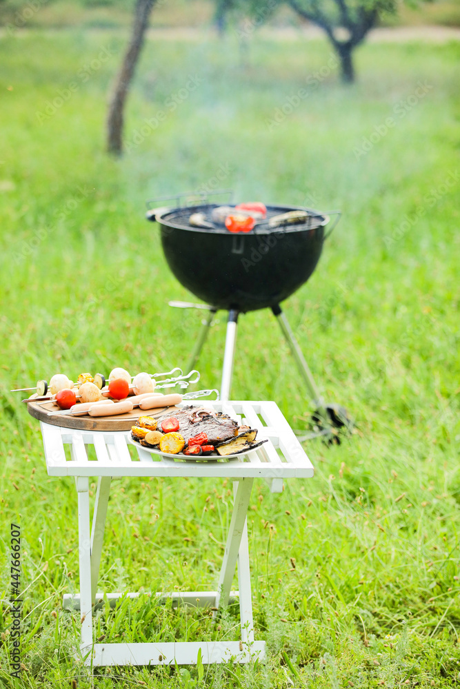 Table with tasty grilled food outdoors