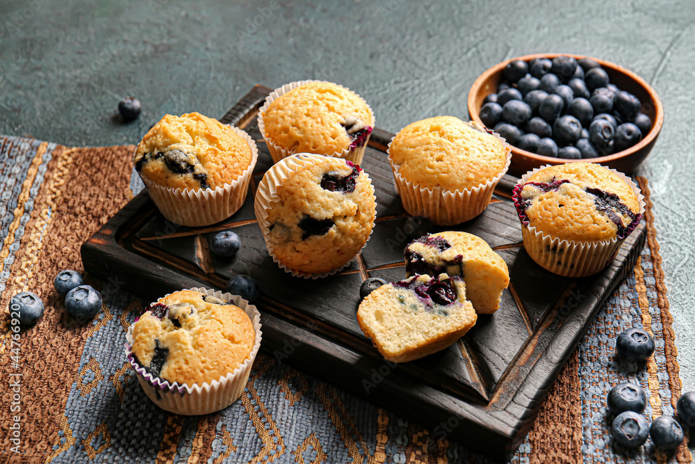 Composition with tasty blueberry muffins and berries on dark background