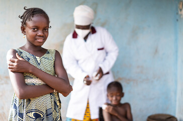 smiling beautiful little african girl holding a patch on her shoulder after getting a flu shhot , wi