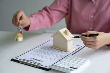 woman holding house keys real estate agent along with documents to rent or buy a house woman working home loan at her office