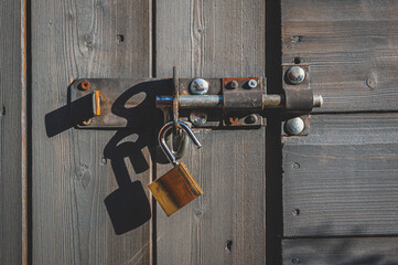 Brass padlock with bolt lock on wooden door. No key.