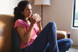 © Wavebreak Media - Mixed race woman sitting on sofa and drinking coffee