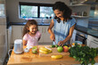 © Wavebreak Media - Happy mixed race mother and daughter cooking together in kitchen